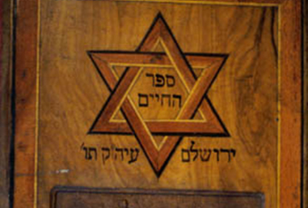 Hebrew book with wood cover with inlaid design and carving. Carved temple at bottom front, above is an inlaid Star of David.