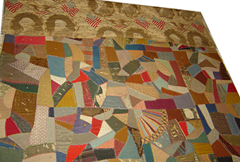 Crazy quilt with one side made of Centennial print fabric with images of George Washington and Benjamin Harrison and the dates 1789 and 1889. The patterning has light american flag imagery with a seemingly random polygonal pattern with all kinds of colors in the center.