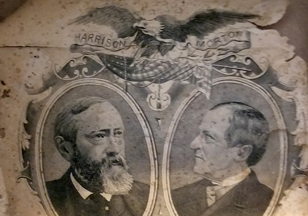 Photograph of the inside of the top hat used in benjamin harrison and levi morton's campaign, which bears a portrait of each of them decoratively framed above the white house with a bald eagle watching over. Inside at top of hat is a paper showing images of Benjamin Harrison on the left and Levi P. Morton on the right. Top center of paper is an eagle and bottom is image of White House. The paper is torn at top right and has brown spots.