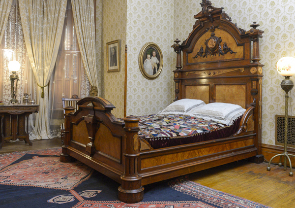 Original Harrison large rosewood and satinwood Renaissance Revival bed. Satinwood panel in tall head board. Large Egyptian medallion in center of head board that matches smaller medallions in chairs. The head board is 8 feet tall with squared feet. Squared urn design on foot board. Foot board has round massive legs. Ornamental pieces in medallions, scrolls, etched designs, etc.