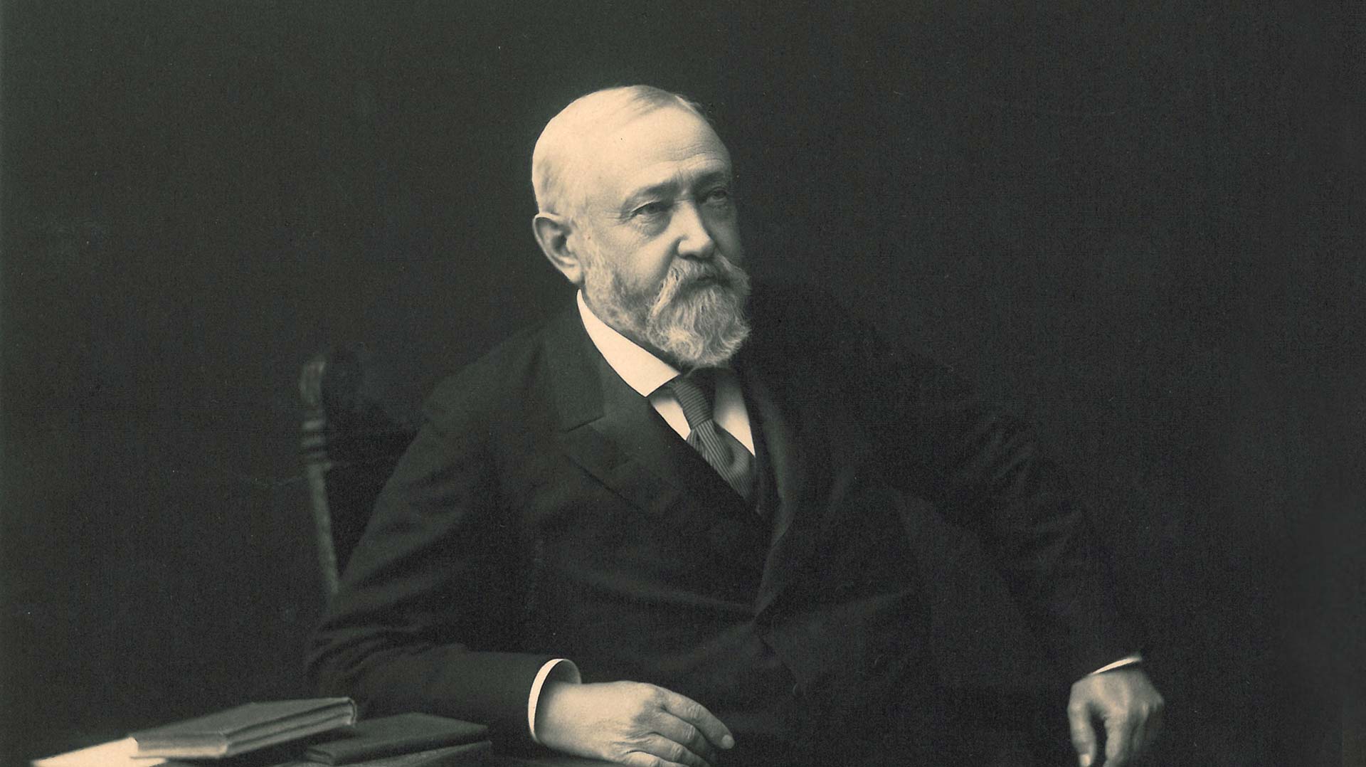 Benjamin Harrison seated in a chair with a table