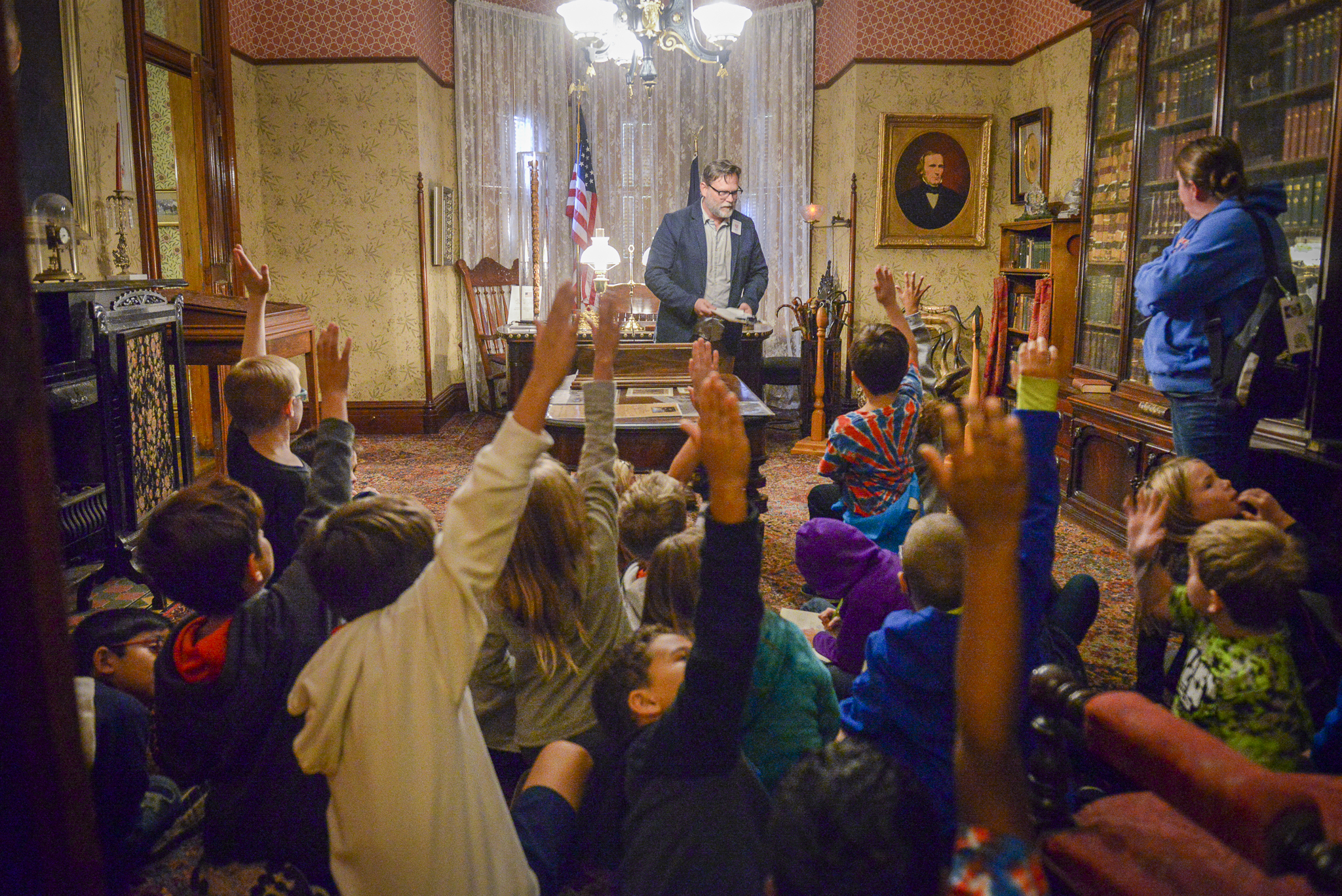 Students raising hands at a Presidential Site tour, in the office of Benjamin Harrison.