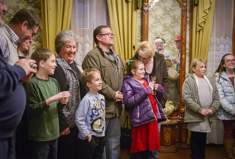 Photo of a smiling family gathered in the Benjamin Harrison Home during the Candlelight Theatre.
