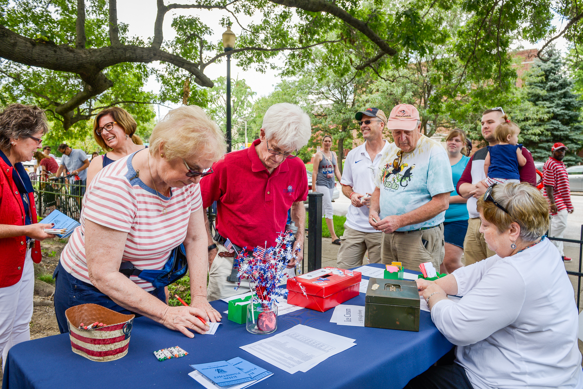 Photo of several seniors gathered at a table, perusing the items while a vendor looks on.