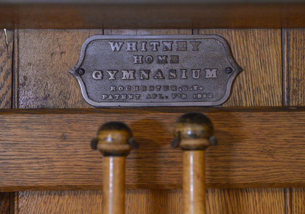 Oak case with iron dumbbell shaped weights (5) on ropes to be pulled, eight sets of wooden dumbbells and pair of Indian clubs. Metal plate: 