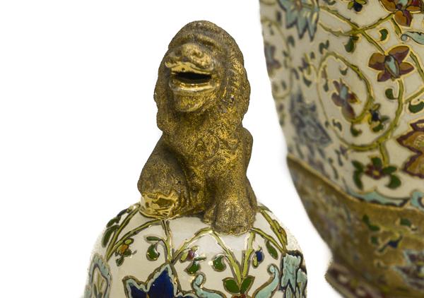 Matched pair of porcelain rose jars (Potpourri jars) with octagon shape, so called as they were filled with dried rose petals. They are Hungarian and have a gold lion on top. The lions are painted with a rough finish gold paint. They have their mouths open and one paw up on a bright and smooth gold ball. Ornately painted with red, blue, and dark yellow flowers with green leaves and vines on white background with gold trim at top.