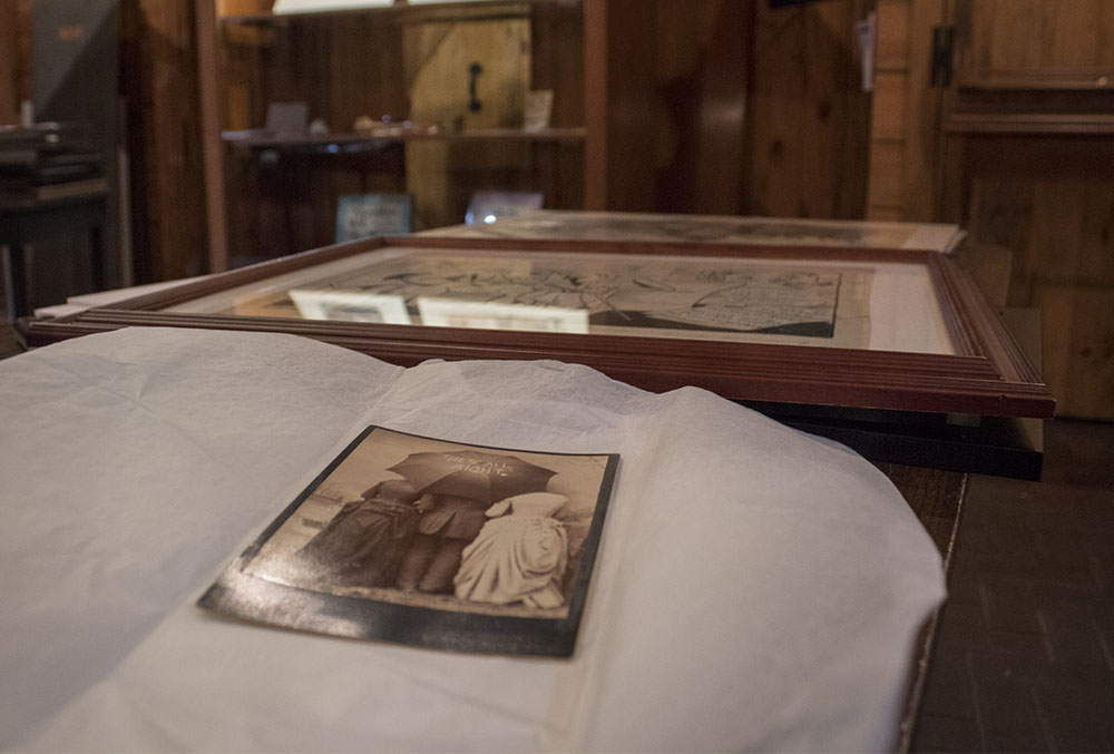 Photographic image of a photograph on a table. Museum cases are in the background.