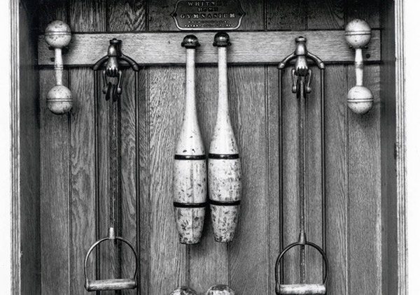 Oak case with iron dumbbell shaped weights (5) on ropes to be pulled, eight sets of wooden dumbbells and pair of Indian clubs. Metal plate: 
